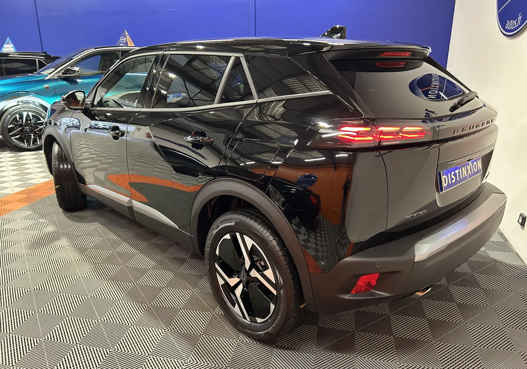 Peugeot 2008 hybride noire vue 3/4 arrière droit, avec feux LED allumés et jantes noires distinctives.
