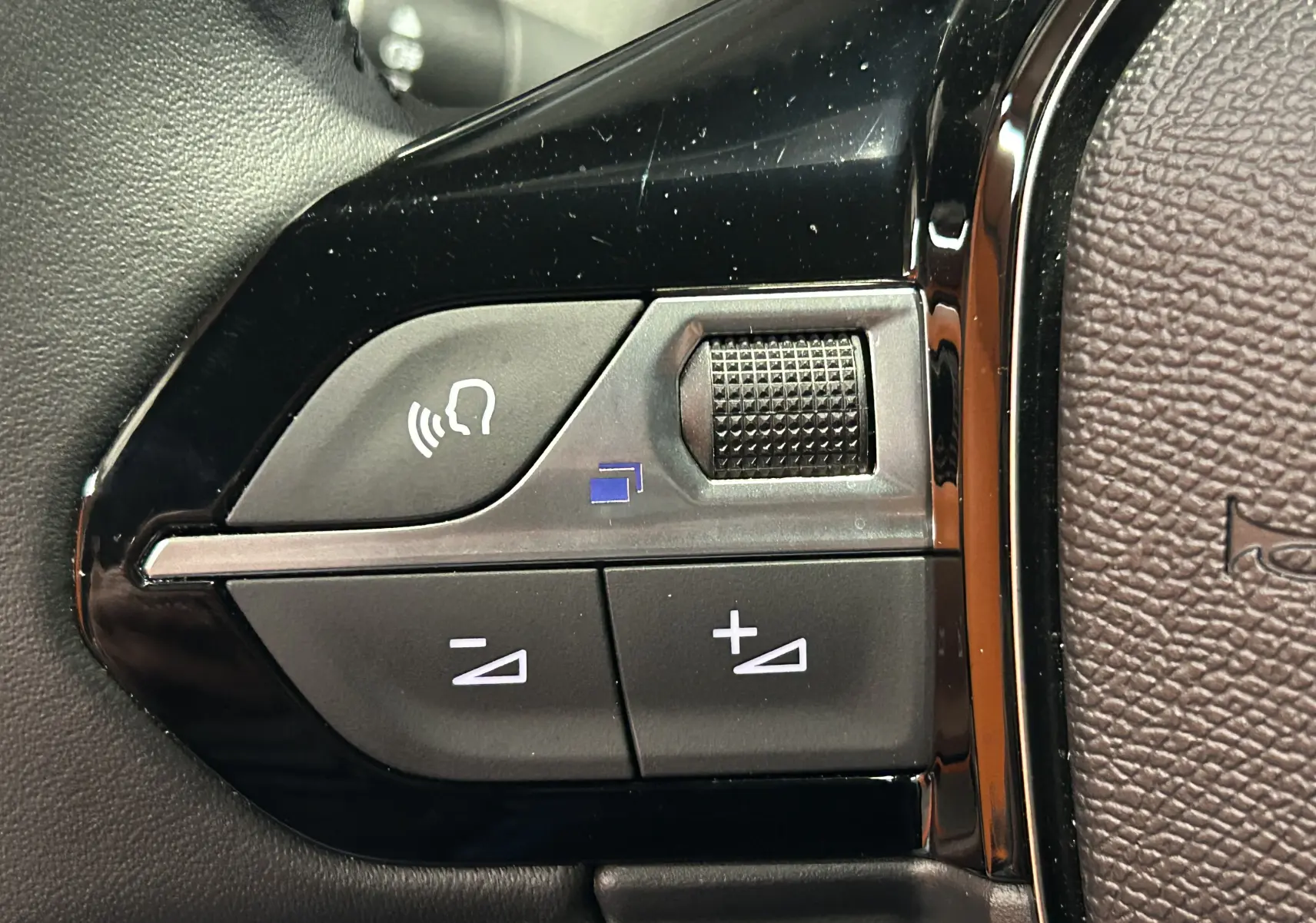 Gros plan sur les commandes de volume et téléphone sur le volant noir du Peugeot 2008 II Hybrid 110 Allure.