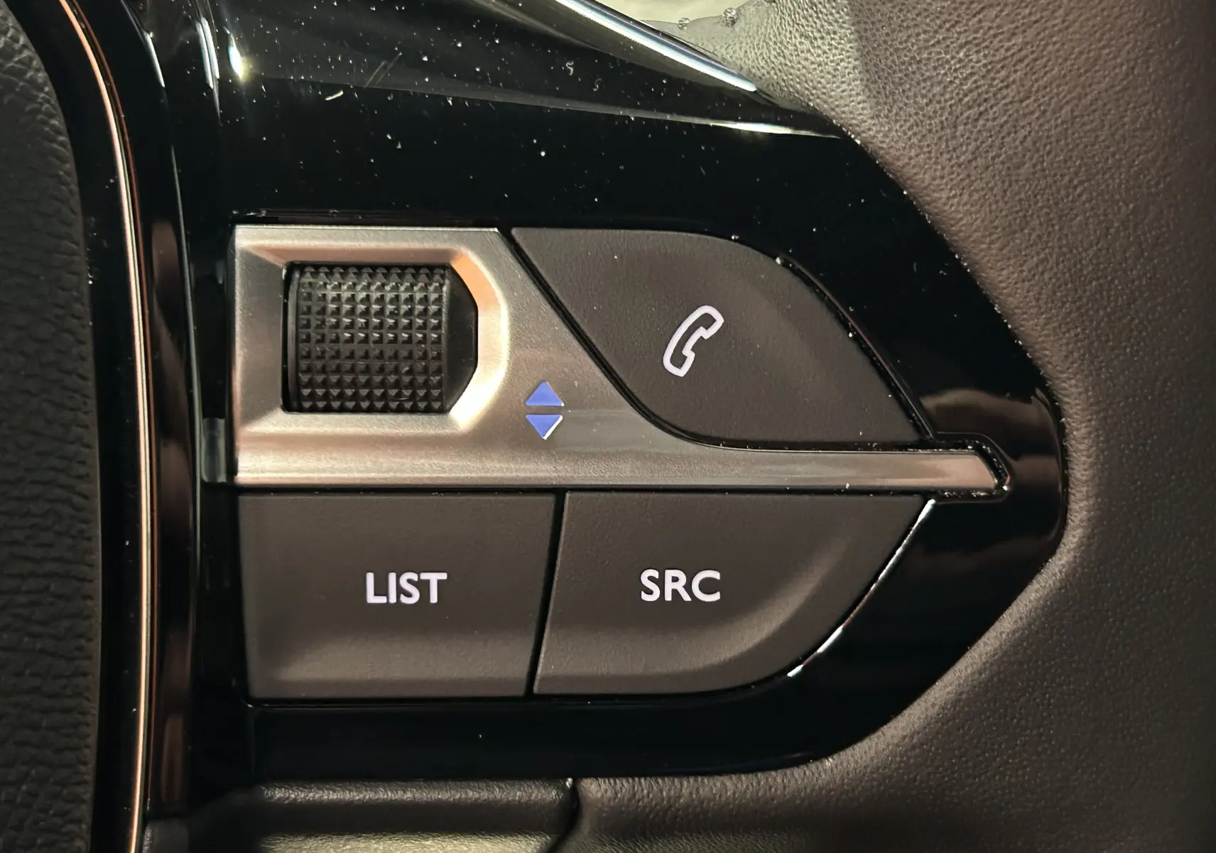 Gros plan sur les commandes multifonctions noires et argentées au volant du Peugeot 2008 II Hybrid 110 Allure.