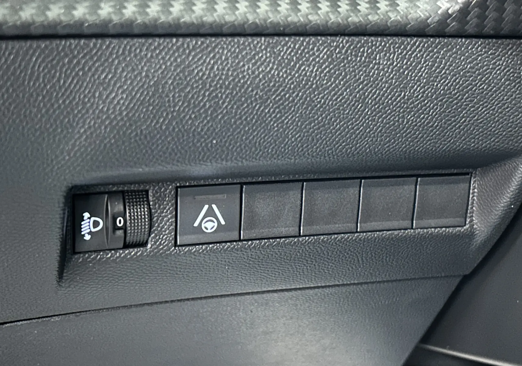 Gros plan sur les commandes de réglage des phares et d’assistance au maintien de voie dans l’habitacle d’une Peugeot 2008 noire.