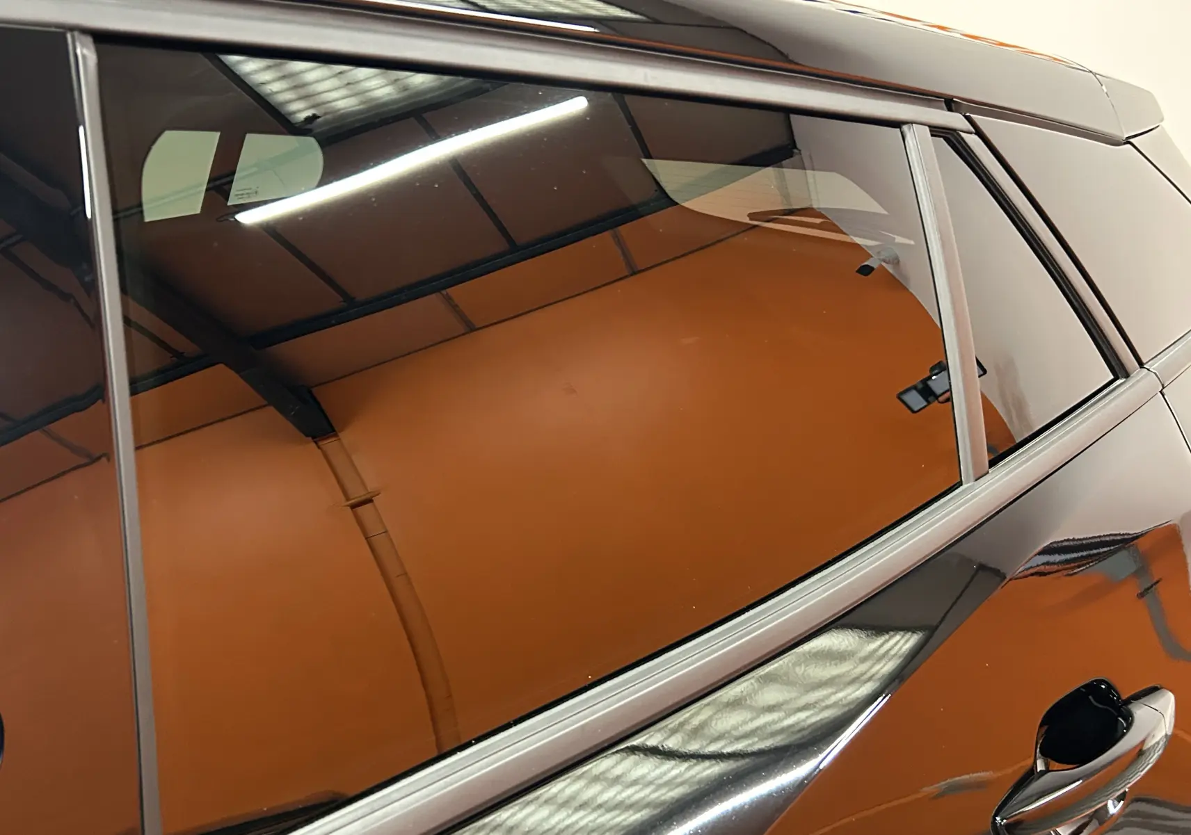 Vue rapprochée du côté gauche arrière d’un Peugeot 2008 noir brillant avec reflet d’éclairage intérieur.