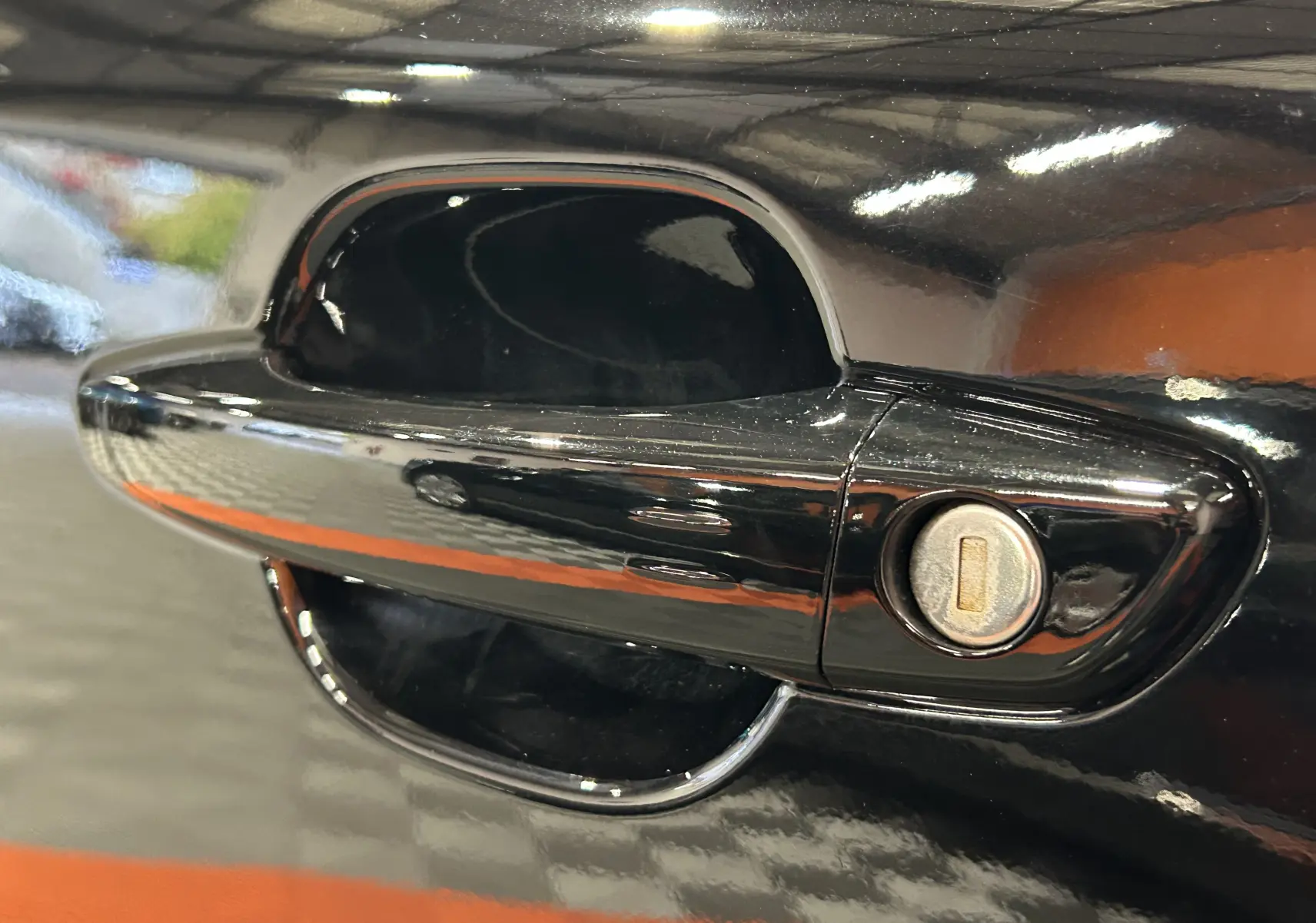 Gros plan sur la poignée de porte noire brillante côté gauche du Peugeot 2008 II Hybrid 110 e-DCS6 Allure.