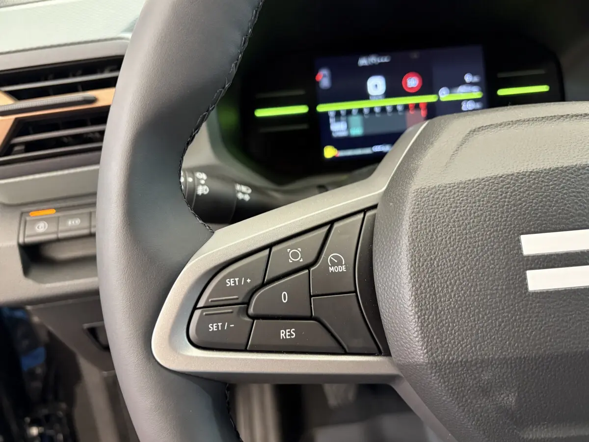Gros plan sur le volant cuir synthétique côté gauche du tableau de bord du Dacia Duster noir 2025 avec commandes multifonctions.