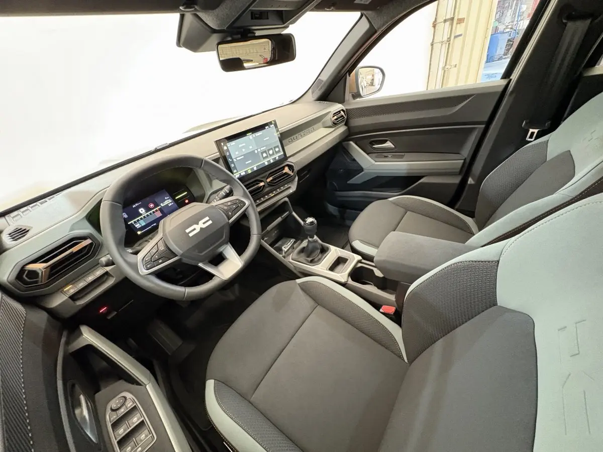 Intérieur du Dacia Duster 2025 vue côté conducteur, tableau de bord moderne avec écran tactile et volant multifonctions.