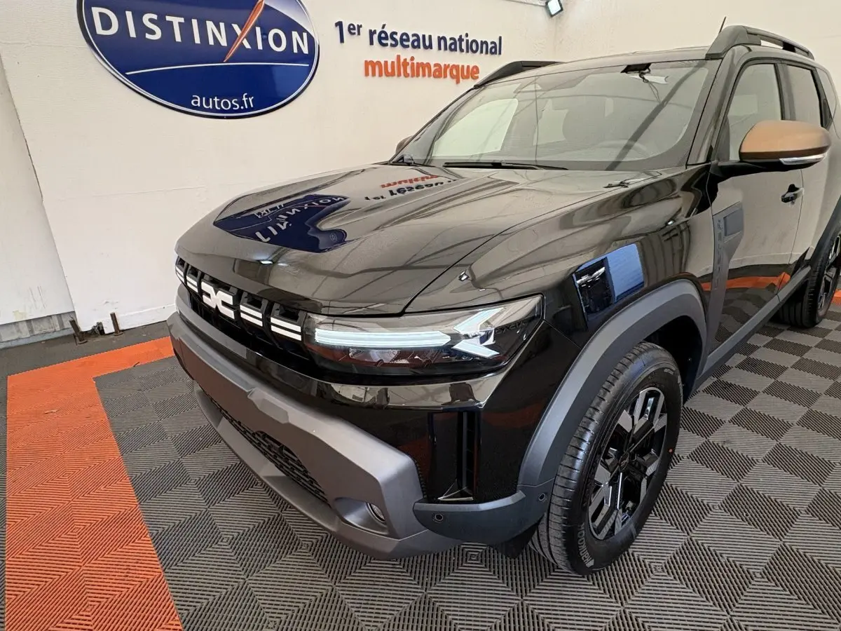 Vue 3/4 avant droit du Dacia Duster 2025 noir avec calandre distinctive et jantes noires en showroom