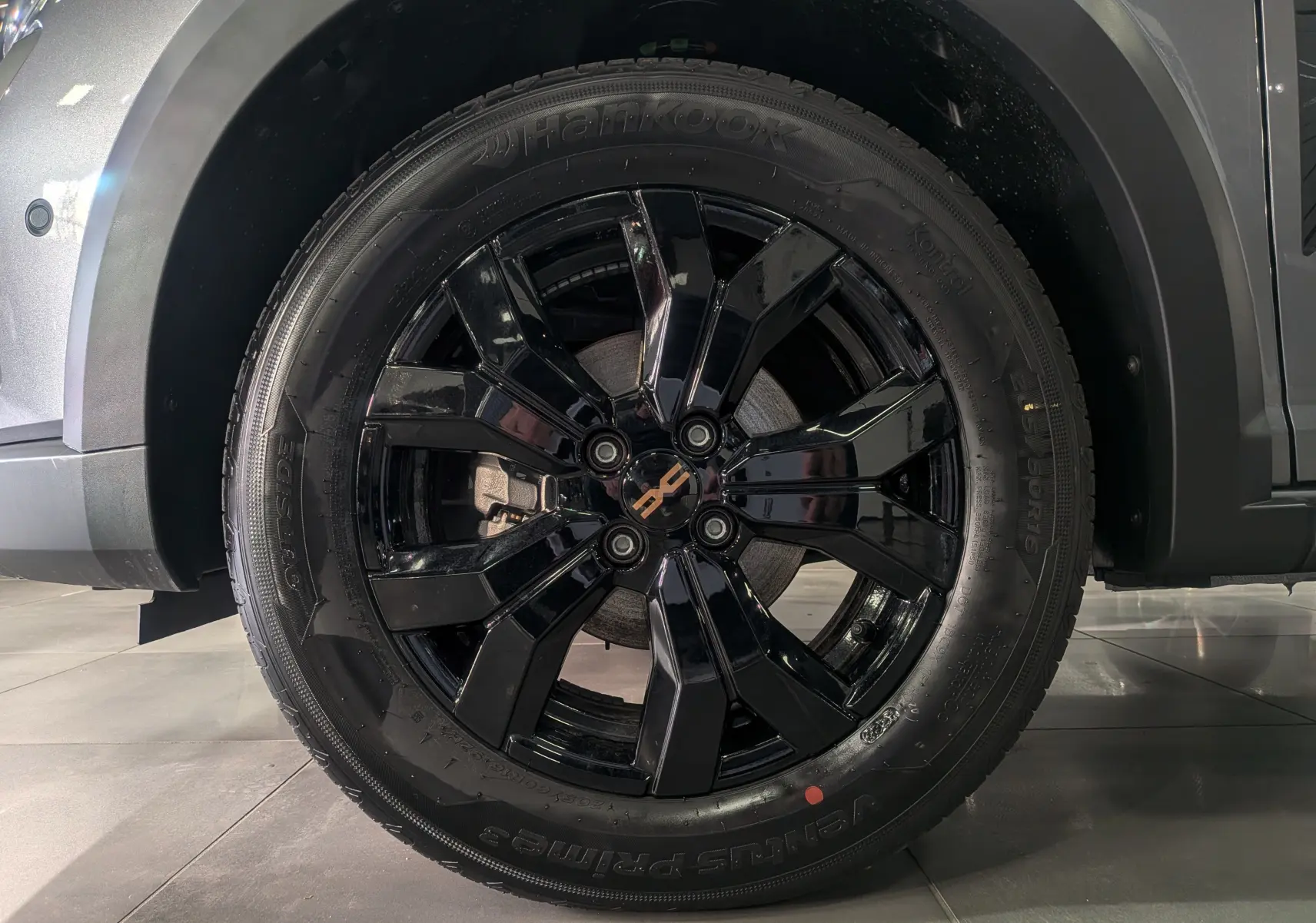 Gros plan sur la roue avant droite noire brillante d'une Dacia Sandero Stepway Gris Schiste 2025.