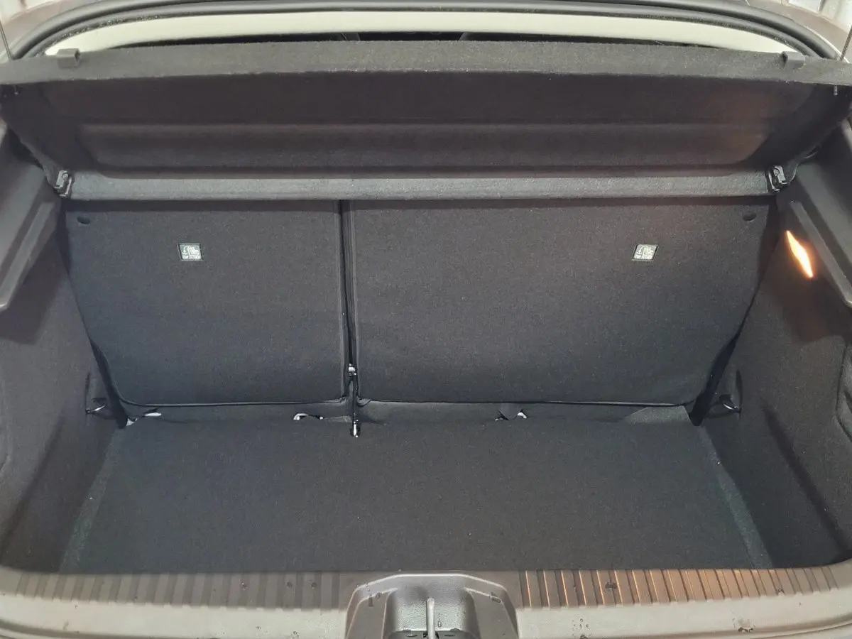 Coffre ouvert vu de l'arrière d'une Renault Clio gris foncé, montrant la banquette arrière et l'espace de chargement.