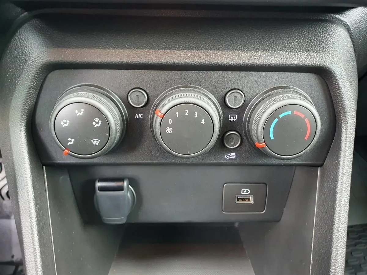 Vue rapprochée des commandes de climatisation manuelle et prise USB du tableau de bord du Dacia Jogger kaki 2024.