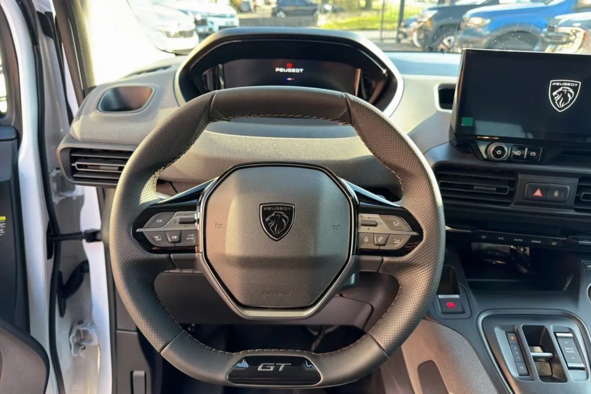 Vue intérieure centrée sur le volant cuir multifonctions du Peugeot Rifter GT Plus avec tableau de bord et écran tactile.