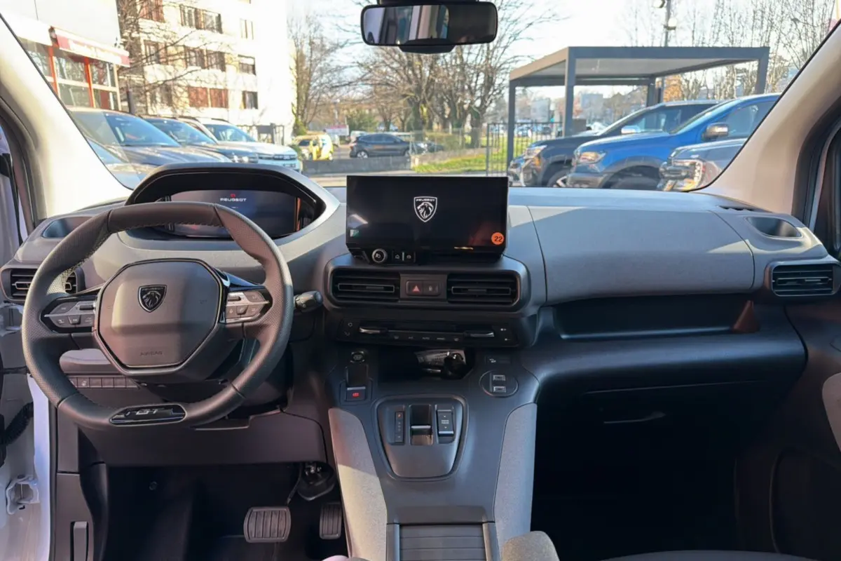 Vue intérieure avant du Peugeot Rifter blanc kaolin 2025, mettant en valeur le volant cuir multifonctions et l’écran tactile central.