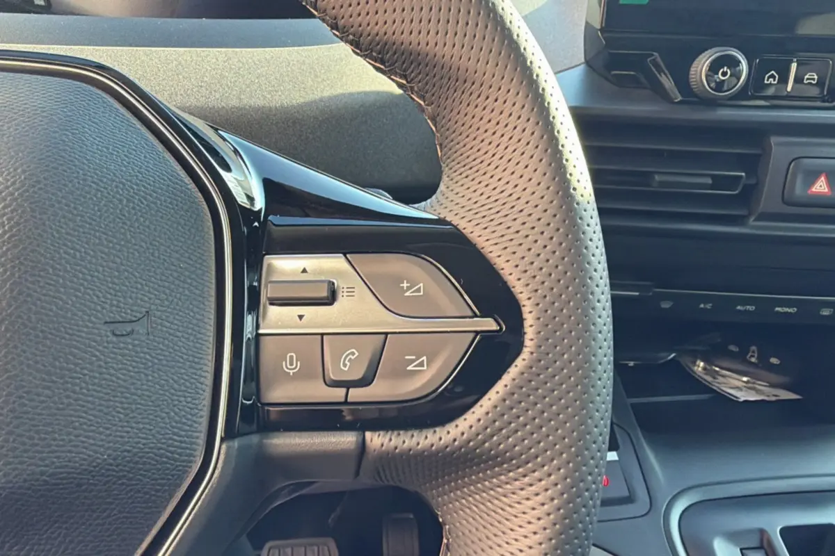 Gros plan sur le volant cuir perforé du Peugeot Rifter 2025, avec commandes multifonctions intégrées.