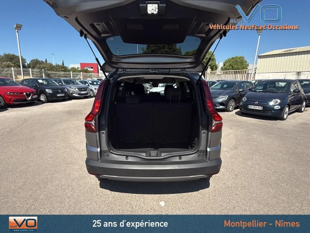 Vue arrière du Dacia Jogger gris 2025 avec coffre ouvert, mettant en valeur l'espace de chargement et les feux arrière.
