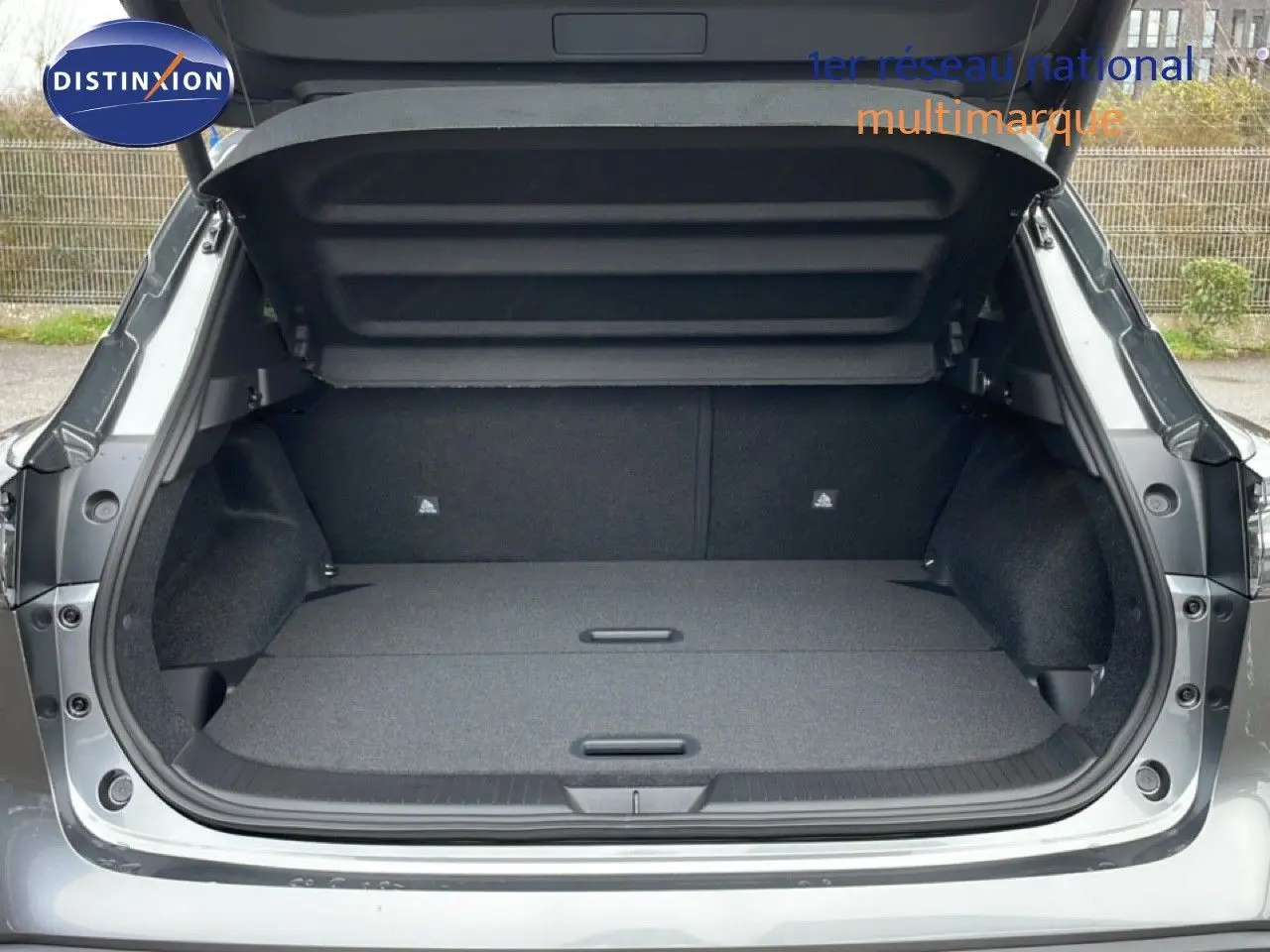 Coffre ouvert vu de l'arrière du Nissan Qashqai gris squale metal, montrant un espace de chargement plat et spacieux.