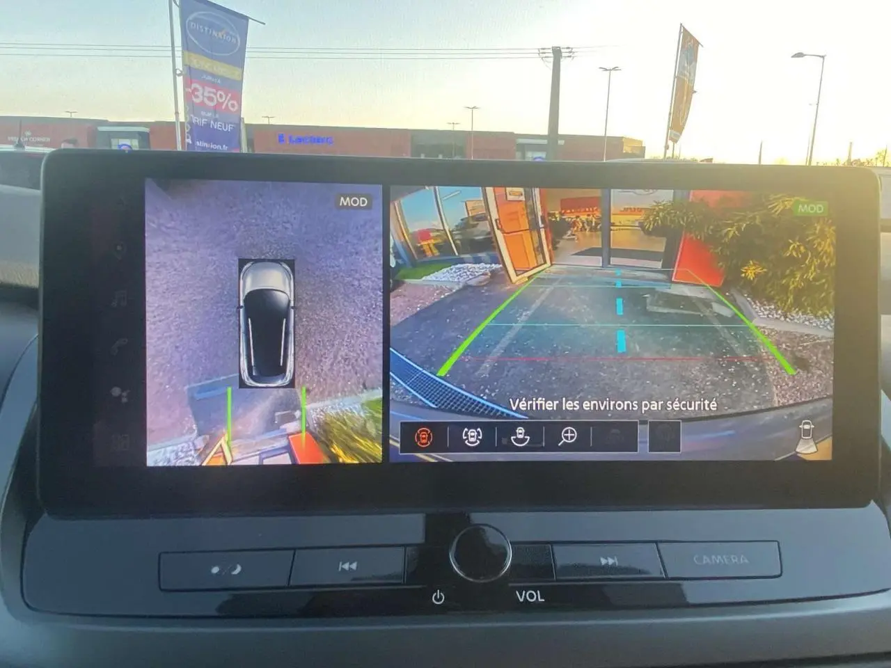 Écran multimédia montrant la caméra de recul et vue 360° du Nissan Qashqai gris ceramic, version 2025, en stationnement.