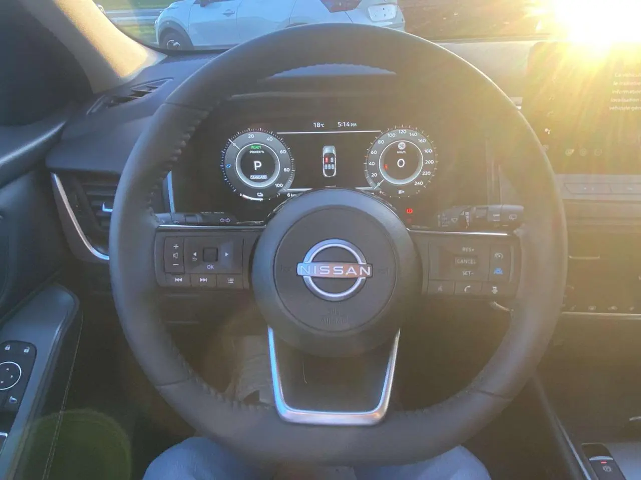 Vue intérieure centrée sur le volant du Nissan Qashqai gris Ceramic 2025 avec tableau de bord numérique éclairé.