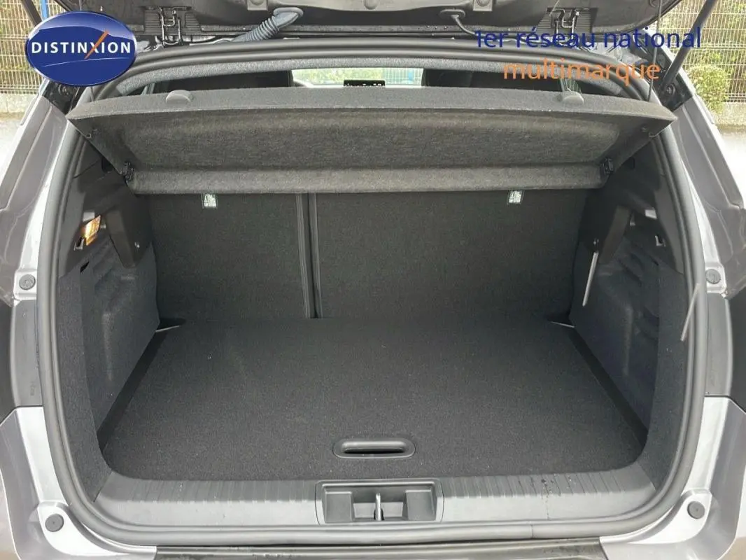 Coffre ouvert vu de l'arrière d'un Renault Captur gris 2025, montrant un espace de chargement propre et spacieux.