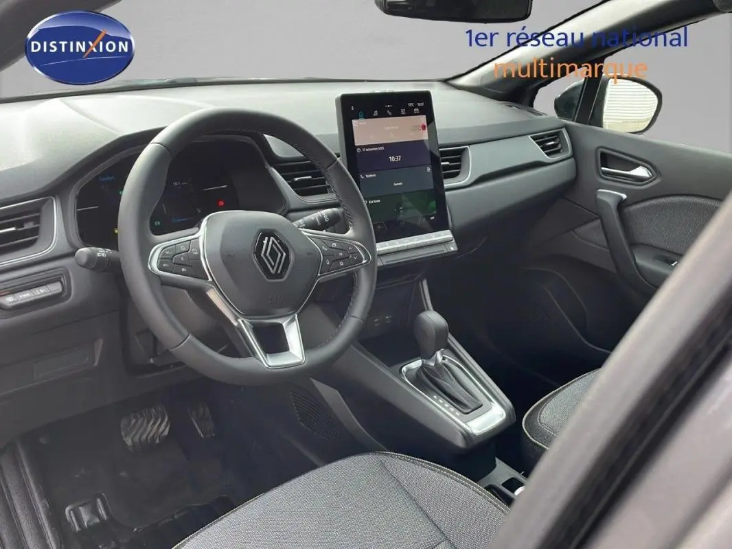 Vue intérieure côté conducteur du Renault Captur gris 2025, volant cuir et écran tactile central visible.