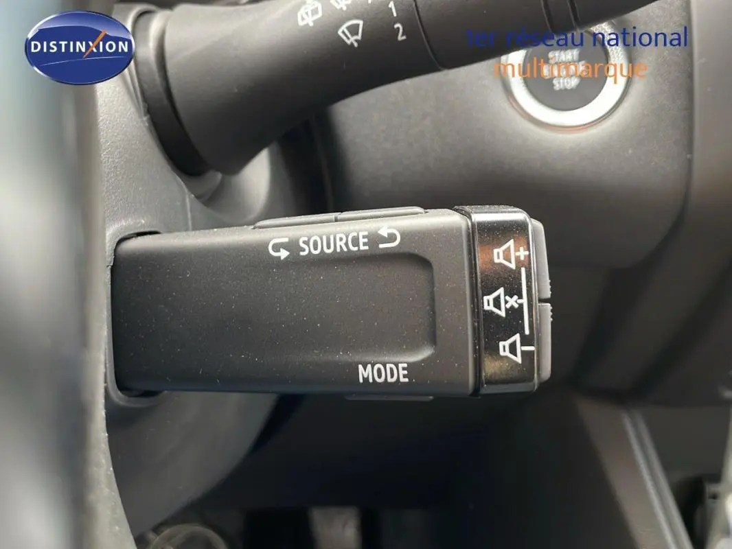 Gros plan sur la commande audio au volant du Renault Captur gris, version hybride 2025, avec bouton source et mode.