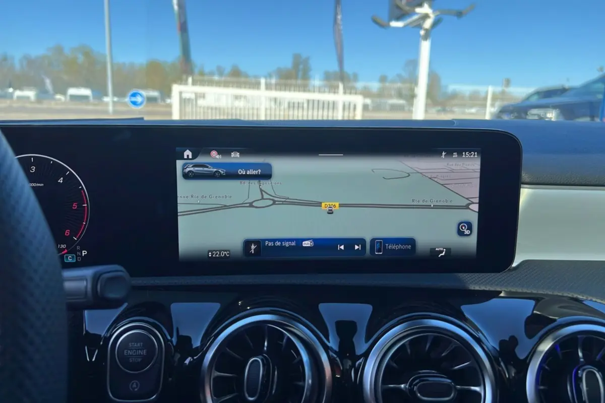 Vue intérieure du tableau de bord de la Mercedes Classe A 200D avec écran GPS large et aérateurs ronds noirs brillants.