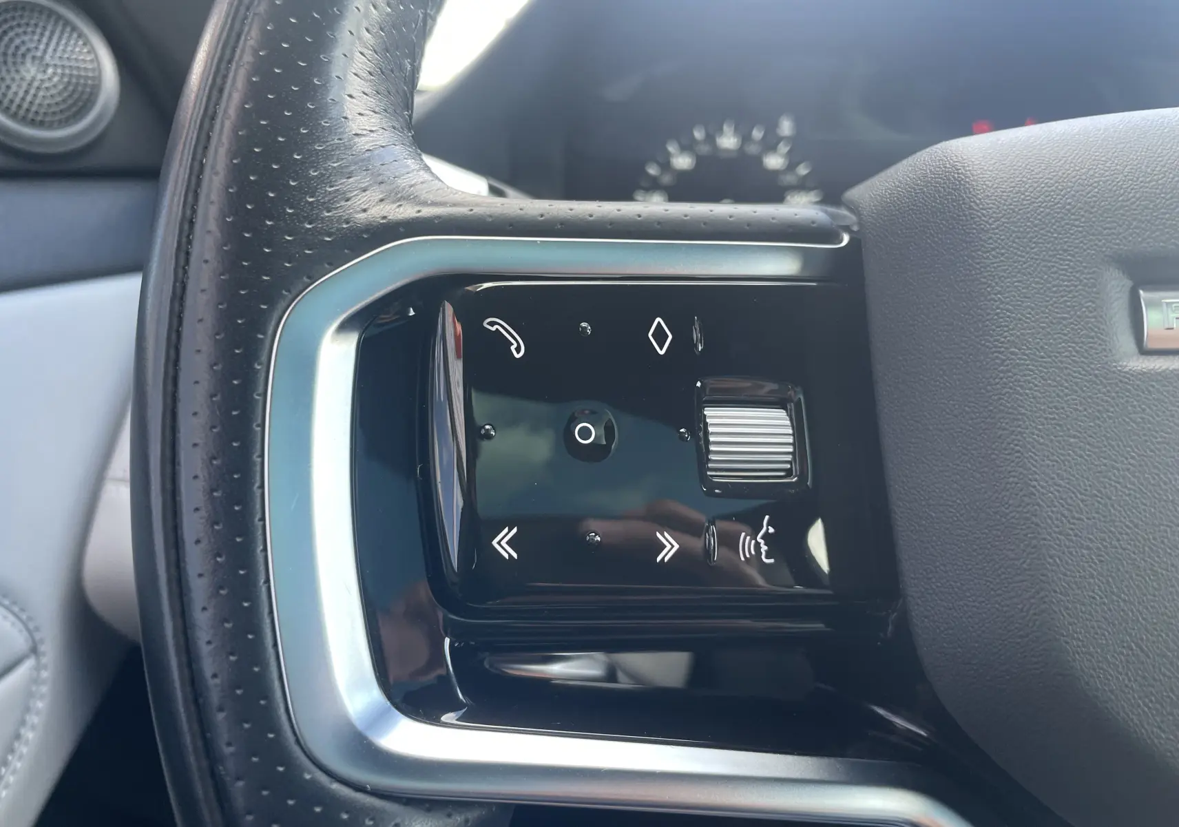 Gros plan sur les commandes tactiles noires du volant en cuir perforé du Range Rover Evoque 2022, finition R-Dynamic SE.