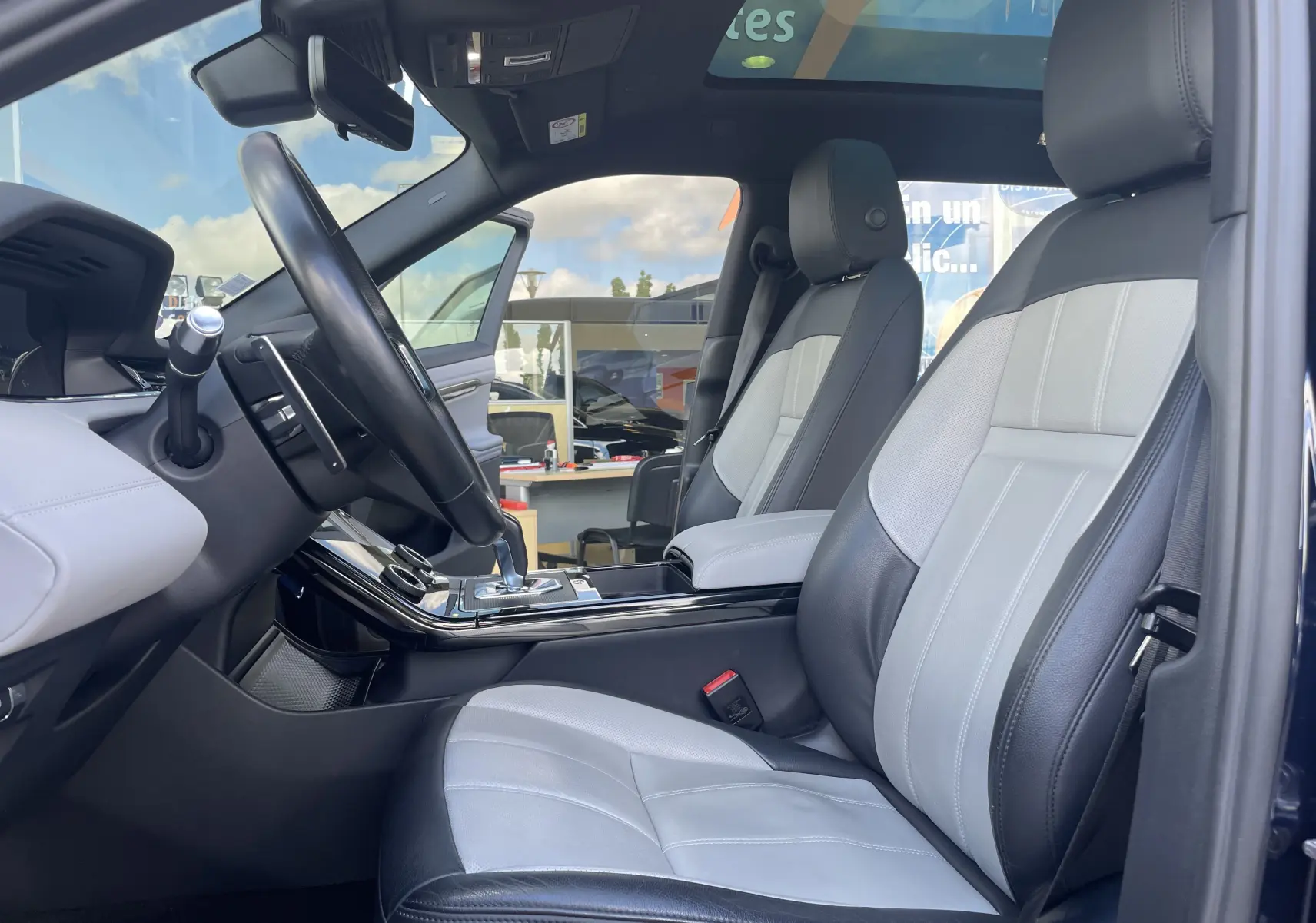 Vue intérieure côté conducteur du Range Rover Evoque 2022 en Portofino Blue, sièges cuir bicolores gris et noir.