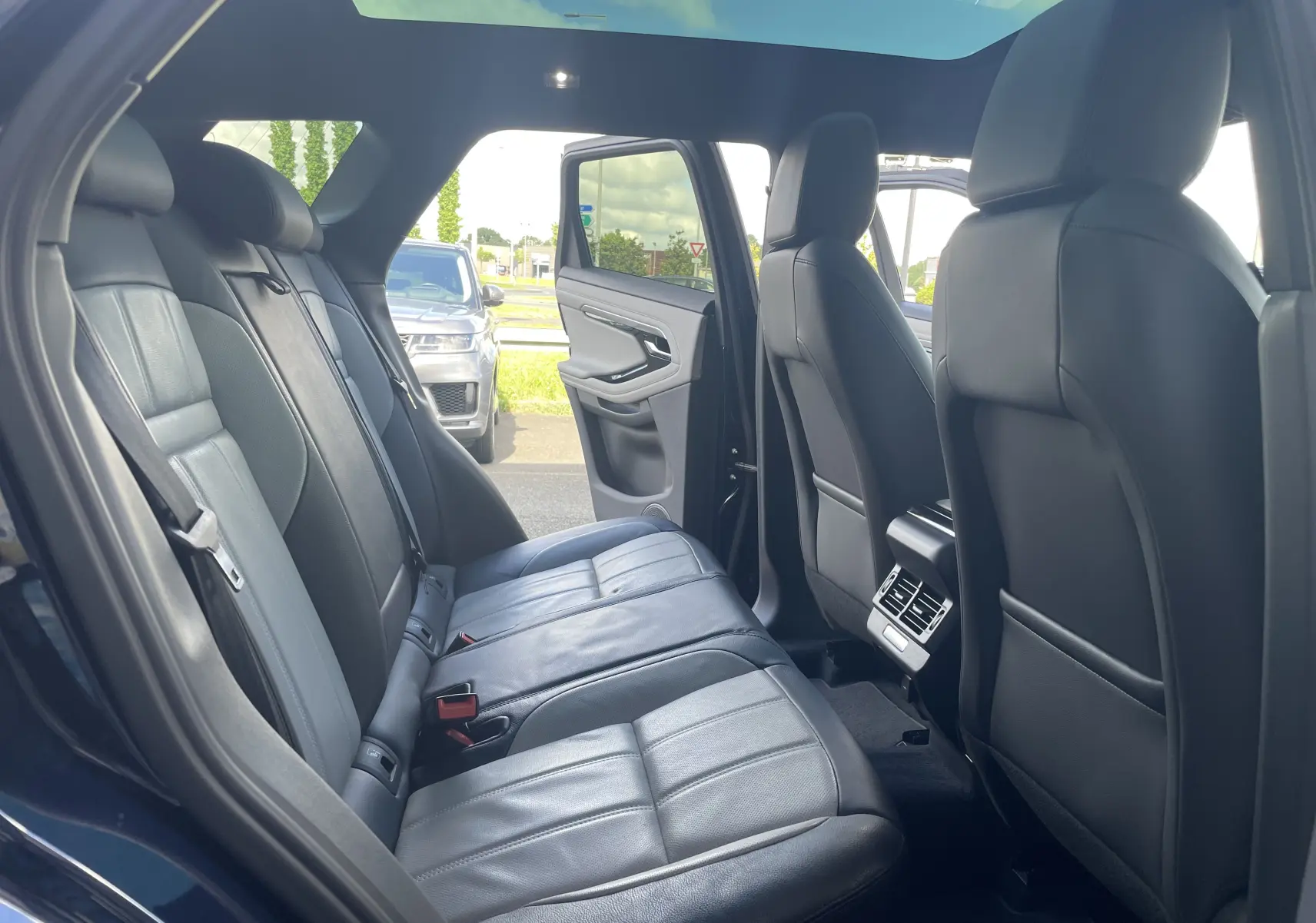 Intérieur arrière du Range Rover Evoque 2022 en Portofino Blue, sièges cuir noirs et toit ouvrant panoramique visible.