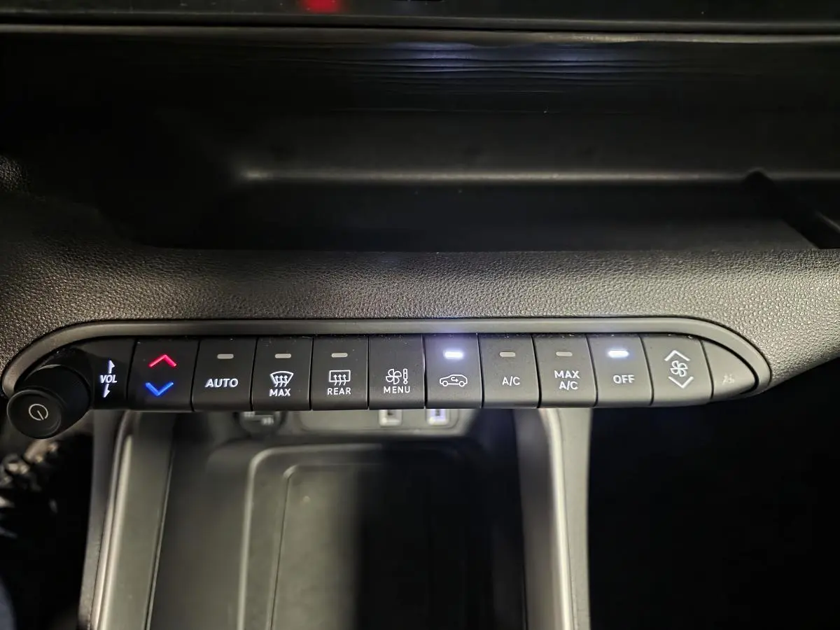 Vue rapprochée de la commande de climatisation noire du Jeep Avenger 2025 avec boutons rétroéclairés blancs et bleus.