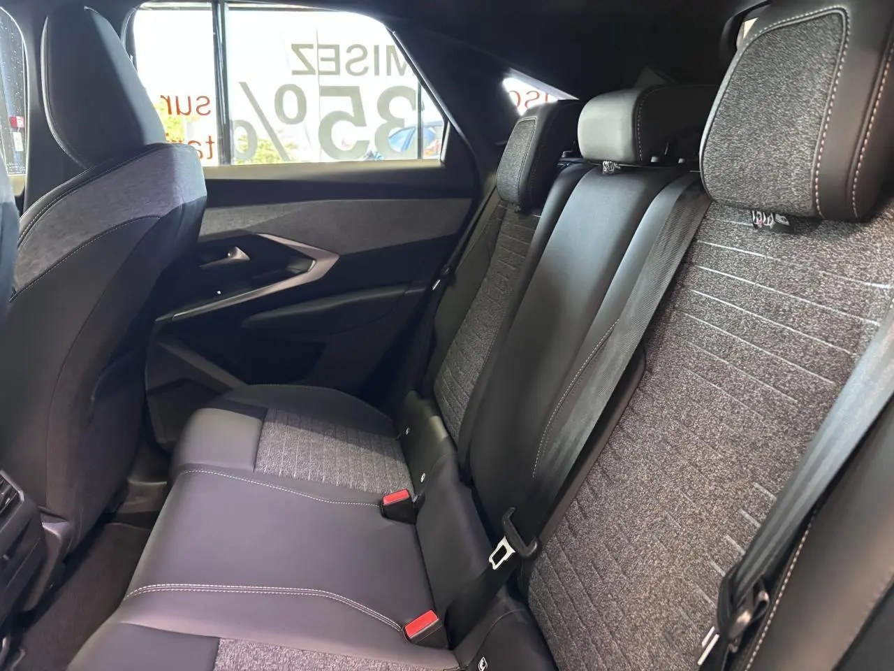 Vue intérieure côté droit des sièges arrière gris tissu et noir cuir du Peugeot 3008 hybride 2026 avec ceintures de sécurité visibles.