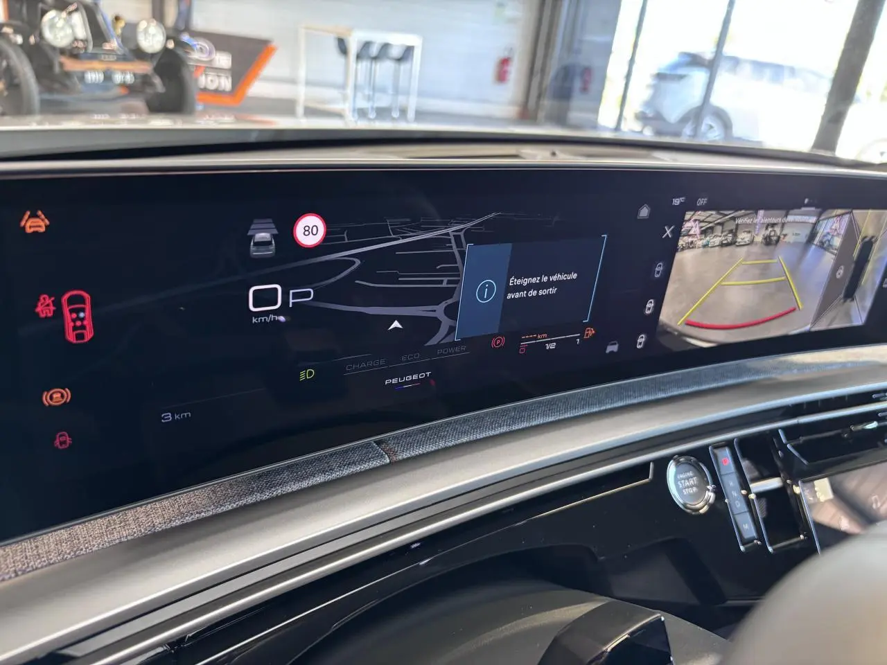 Vue rapprochée de l'écran numérique du tableau de bord du Peugeot 3008 hybride blanc, affichant la caméra de recul et les alertes.