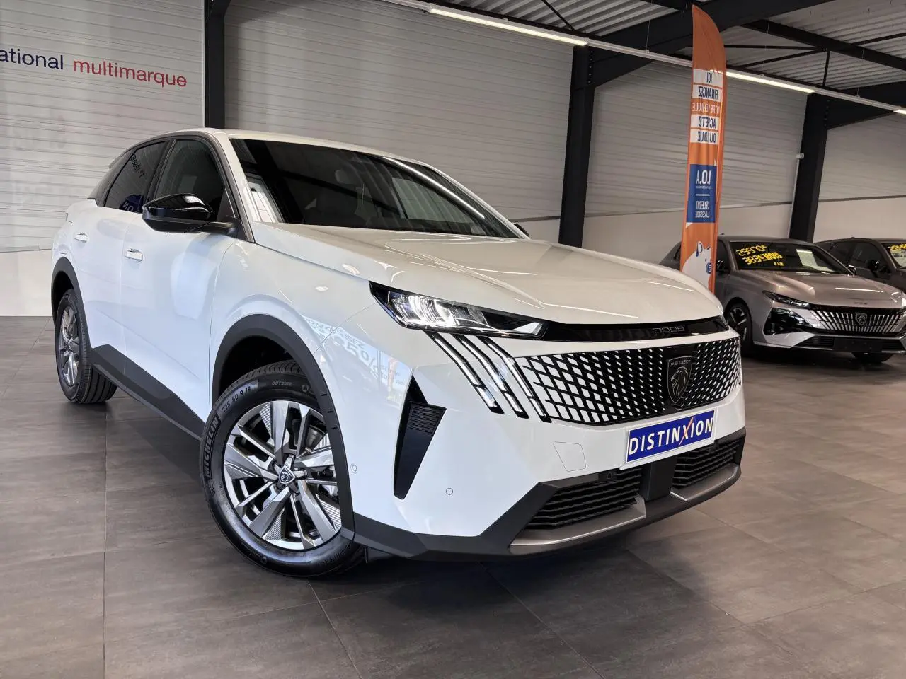 Peugeot 3008 blanc vue 3/4 avant en showroom, calandre noire laquée avec feux LED griffés distinctifs.
