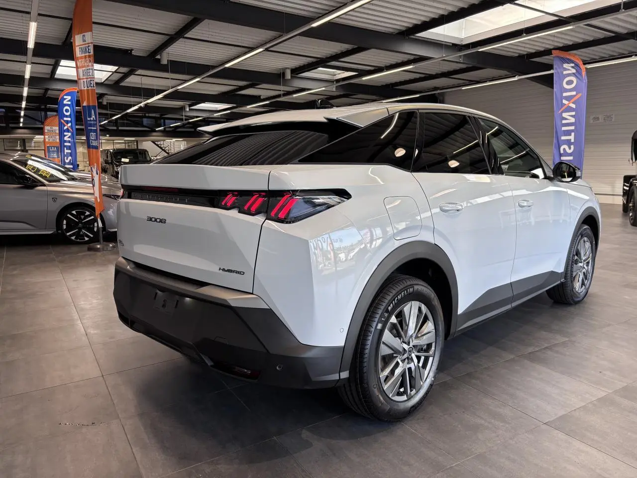 Vue 3/4 arrière droite du Peugeot 3008 blanc hybride avec feux arrière LED à 3 griffes et jantes alliage 18 pouces.