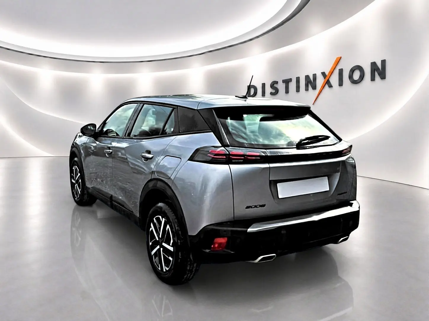 Peugeot 2008 gris en 3/4 arrière droit, avec feux arrière LED et jantes noires à motifs argentés.
