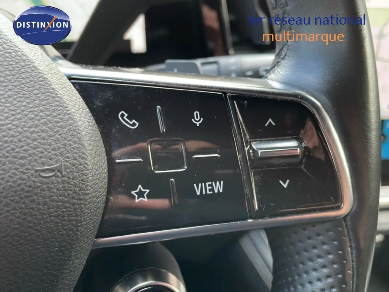 Gros plan sur les commandes gauche du volant en cuir noir du Renault Espace VI gris schiste, avec boutons multifonctions et molette.