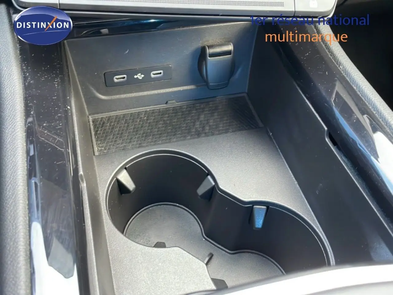 Gros plan sur la console centrale noire du Renault Espace 2024, avec porte-gobelets et ports USB visibles.