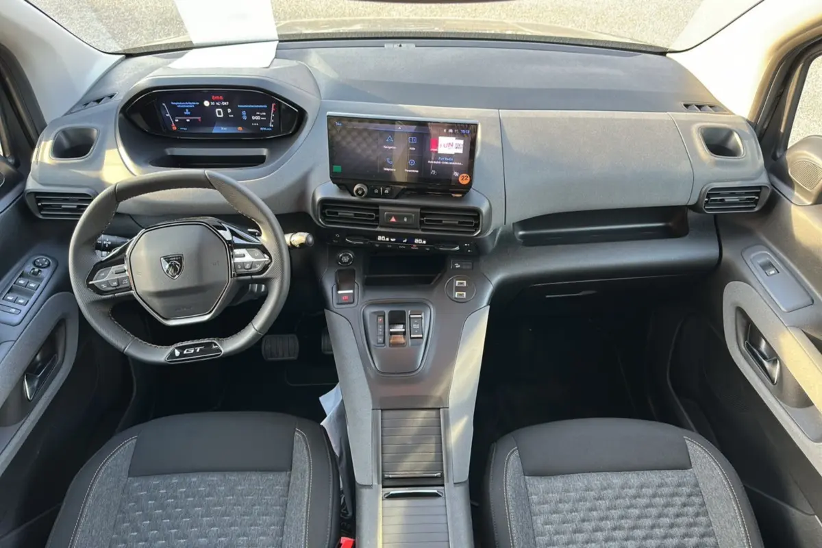 Vue intérieure avant du Peugeot Rifter GT Plus 2025, tableau de bord moderne avec écran tactile et volant cuir multifonctions.