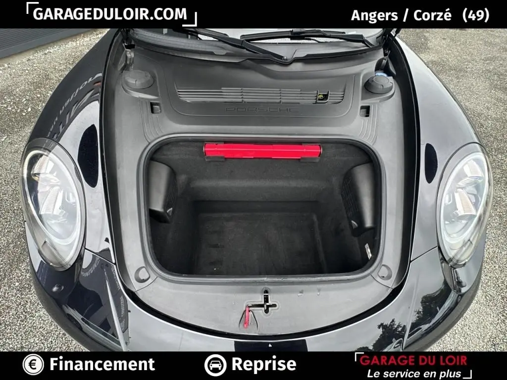 Vue plongeante sur le coffre avant ouvert d'une Porsche 911 Carrera GTS Coupé noire, avec feux ronds visibles.