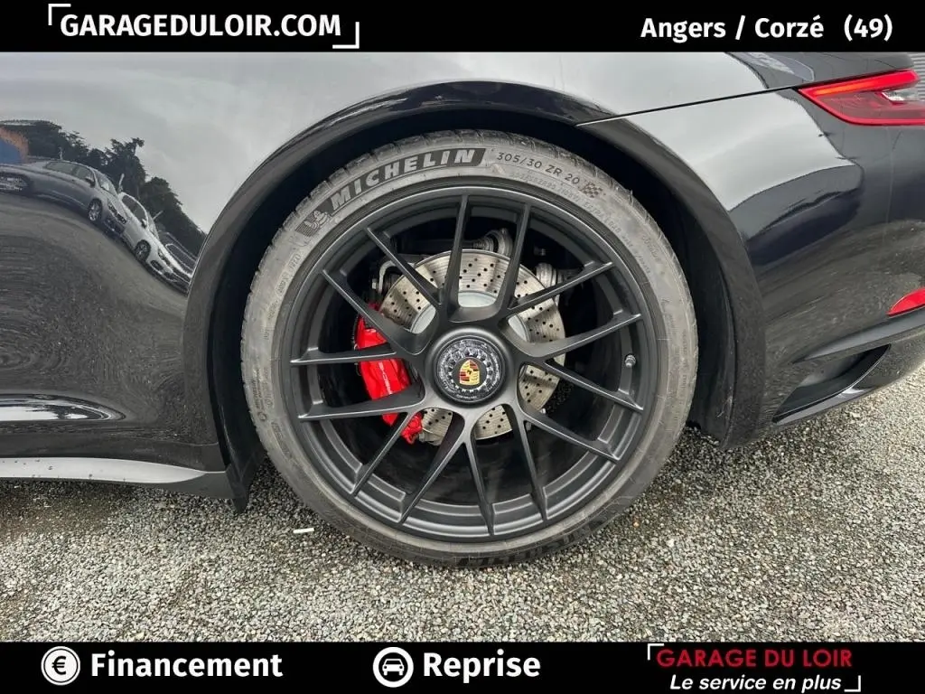 Gros plan sur la roue arrière droite noire d'une Porsche 911 Carrera GTS Coupé 2018 avec étrier de frein rouge visible.