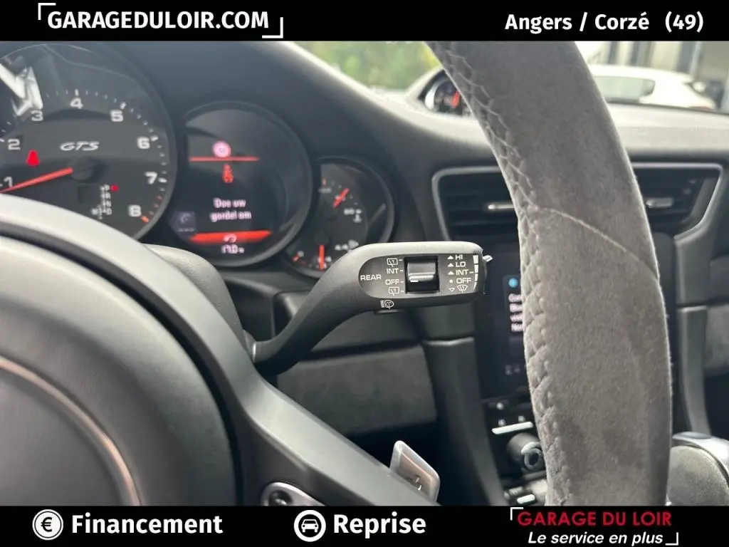 Gros plan sur le tableau de bord et le volant en alcantara gris d’une Porsche 911 Carrera GTS Coupé 2018, intérieur noir.
