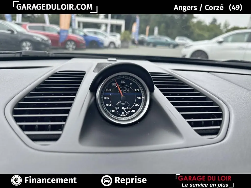 Gros plan sur l’horloge centrale noire du tableau de bord d’une Porsche 911 Carrera GTS Coupé 2018, intérieur gris.
