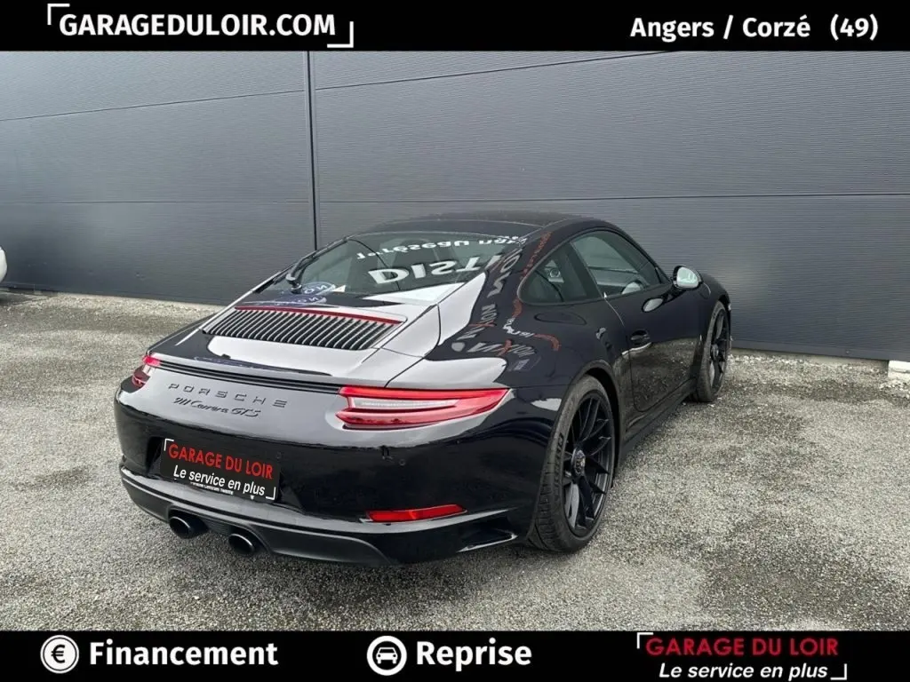 Vue 3/4 arrière droite d'une Porsche 911 Carrera GTS Coupé noire brillante avec jantes noires et feux arrière LED.