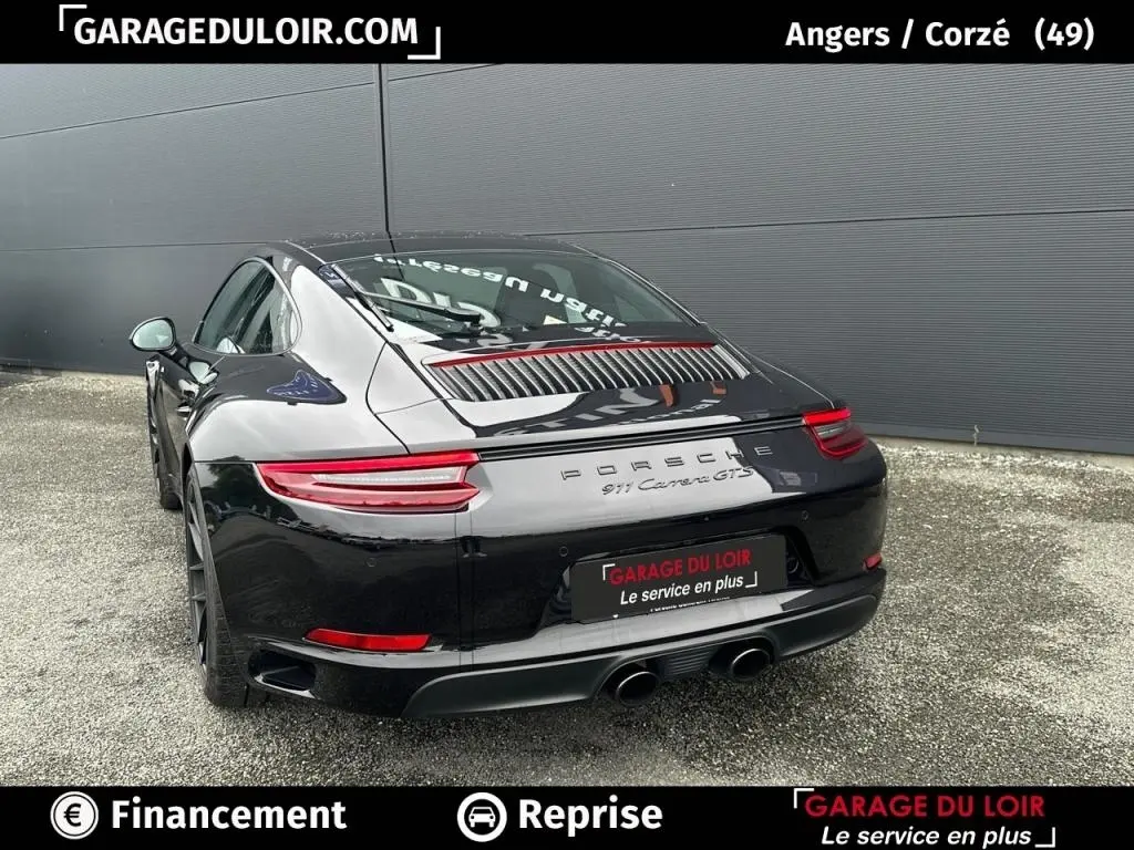 Vue 3/4 arrière droite de la Porsche 911 Carrera GTS Coupé noire, avec feux arrière LED et double sortie d’échappement centrale.