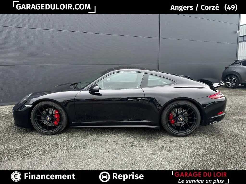 Vue latérale droite d'une Porsche 911 Carrera GTS Coupé noire avec jantes noires et étriers de frein rouges.
