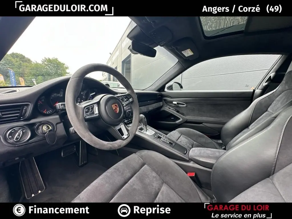 Vue intérieure côté conducteur de la Porsche 911 Carrera GTS Coupé 2018 avec sellerie alcantara grise et volant sport.