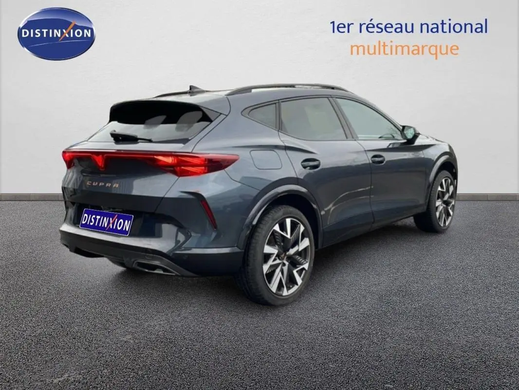 Vue 3/4 arrière droite d'un CUPRA Formentor gris 2025 avec jantes aluminium et barres de toit visibles.