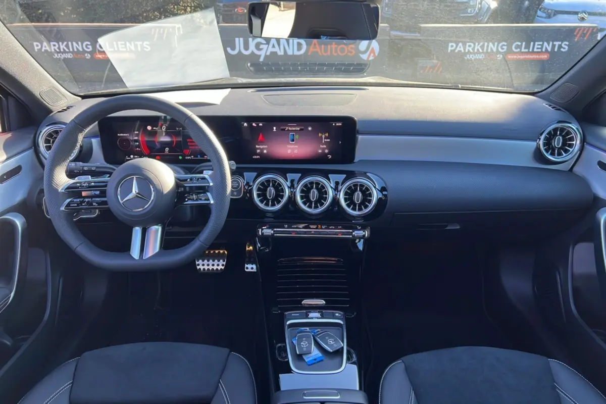 Vue intérieure avant de la Mercedes Classe A 200D Exclusive Design noire, avec tableau de bord numérique et volant multifonctions cuir.