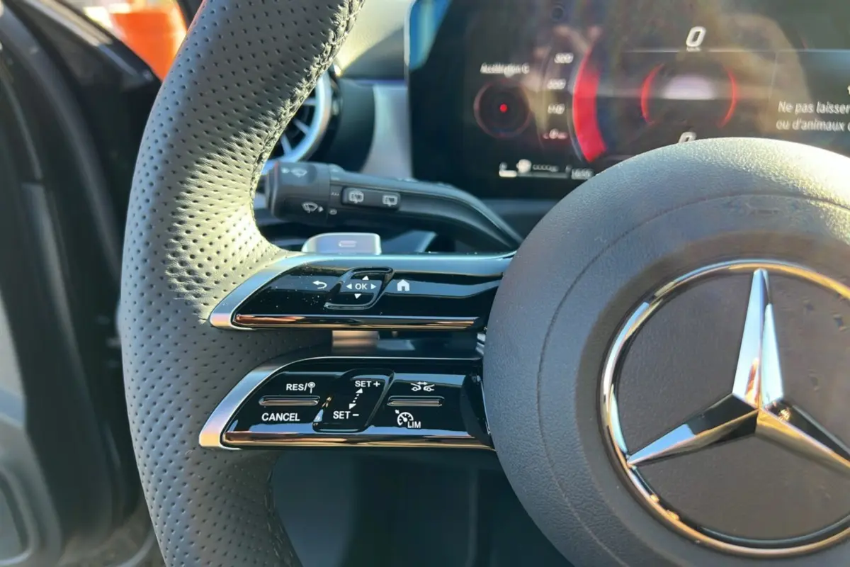 Gros plan sur le volant cuir multifonctions noir de la Mercedes Classe A 200D BVA Exclusive Design avec commandes intégrées.