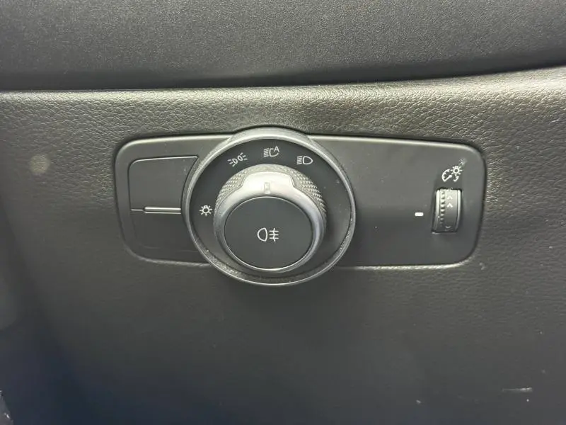 Gros plan sur la commande des phares noire dans l'habitacle de l'Alfa Romeo Tonale gris Vesuvio métallisé.
