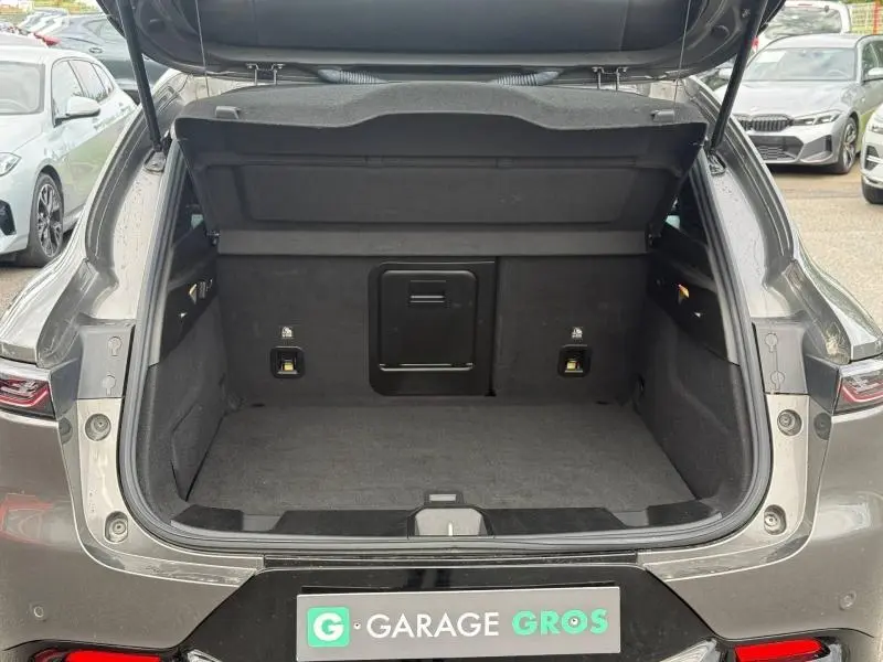 Coffre ouvert vu de l'arrière d'une Alfa Romeo Tonale gris Vesuvio métallisé, montrant un espace de chargement propre et spacieux.