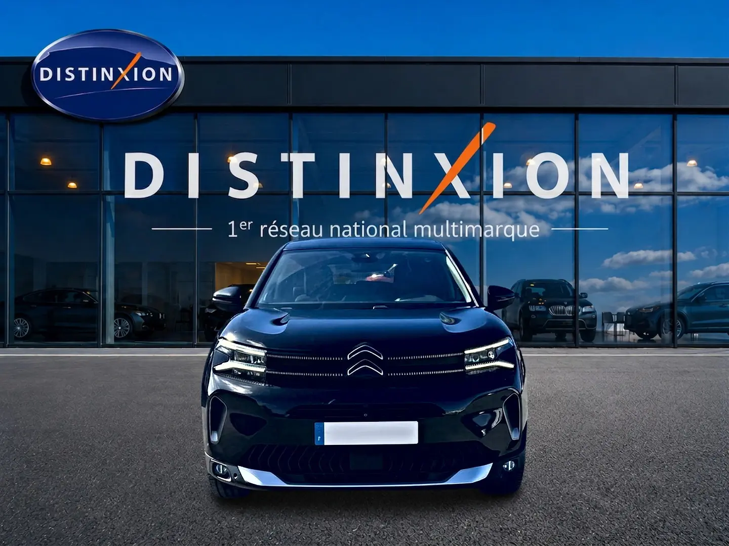Vue frontale d'un Citroën C5 Aircross noir 2024 avec feux LED et calandre distinctive, devant une vitrine Distinxion.