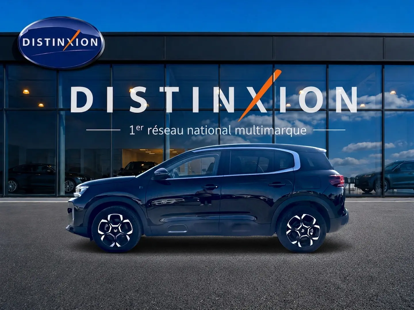 Profil côté gauche d'un Citroën C5 Aircross noir 2024 devant une vitrine avec logo Distinxion.